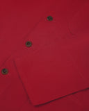 Closer view of mid section of berry red, buttoned organic cotton overshirt from Uskees. Focus on cuff, placket and corozo buttons.