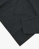 Closer view bottom-right section of black, buttoned ripstop overshirt from Uskees. Focus on cuff, pockets and corozo buttons.