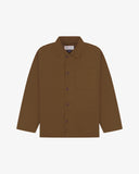 Front flat shot of brown, buttoned organic cotton overshirt. Clear view of chest and hip pockets, corozo buttons and Uskees branding label.