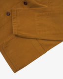View of the hem, sleeve and hip pocket of the 3001 Uskees button-down drill overshirt in buckthorn (mustard yellow).