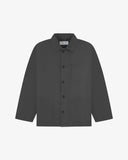 Front flat shot of charcoal-grey, buttoned drill overshirt. Clear view of corozo buttons, 3 pockets and Uskees branding label.