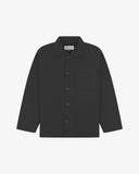 Front flat shot of charcoal-grey, buttoned organic cotton overshirt. Clear view of chest and hip pockets, corozo buttons and Uskees branding label.