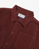 Close-up top-half view of #3001 deep wine berry organic cotton corduroy overshirt. With focus on collar, Uskees brand label and corozo buttons.