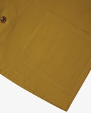 Closer view of mustard-yellow, buttoned organic cotton overshirt from Uskees. Focus on hem, placket, hip pocket and corozo buttons.