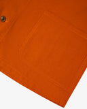 Closer view of bottom-right section of golden-orange, buttoned organic cotton overshirt from Uskees. Focus on pocket and corozo buttons.