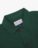 Close-up view of 3001 green, buttoned organic cotton overshirt from Uskees showing corozo buttons, brand label, collar and hanging hoop.