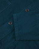Closer view of mid section of petrol blue, buttoned corduroy overshirt from Uskees. Focus on cuff, pockets, corozo buttons and corduroy texture.