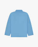 Back view of powder blue, buttoned organic cotton overshirt with view of reinforced elbow area and boxy silhouette.