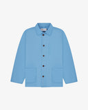 Front flat shot of powder blue, buttoned organic cotton overshirt. Clear view of chest and hip pockets, corozo buttons and Uskees branding label.