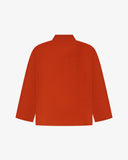 Back view of rust-red, buttoned corduroy overshirt with view of reinforced elbow area and boxy silhouette.