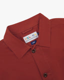 Close-up view of an Uskees clay red overshirt collar with a brand label on a white background