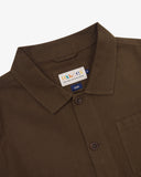 Close up shot of an Uskees brown linen overshirt for men showing the brand label and Corozo buttons in detail.