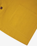 Closer view of mid section of yellow, buttoned organic cotton overshirt from Uskees. Focus on pockets and corozo buttons.