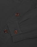 View of the mid-section and sleeve of the 3003 Uskees button-down work shirt in charcoal with focus on cuff, placket and corozo buttons.