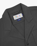 Close-up top-half view of #3006, charcoal-grey organic cotton-drill blazer. With focus on collar, lapels, Uskees brand label and corozo buttons.