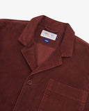 Angled top-half view of #3006, deep wine berry coloured organic corduroy blazer. With focus on collar, notch lapels, breast pocket, Uskees brand label and corozo buttons.