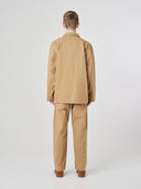Full-length back view of man wearing khaki buttoned organic cotton-twill blazer paired with matching Uskees pants.