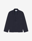 Flat front view of knitted organic cotton midnight blue blazer with 3 patch pockets from Uskees. Clearly showing corozo buttons, two branding labels and 3 pockets on the front.