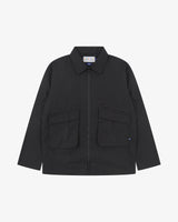 Front view of Uskees black ripstop field jacket showing the chest zip pockets and gusseted pockets with flaps.