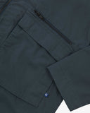 Close up view of Uskees blueberry ripstop field jacket with focus on a zip and gusseted chest pocket , cuff and small branding tab.