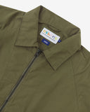 Close up view of Uskees ivy green ripstop field jacket with focus on the collar, zipper, hanging hook and branding label.