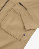 Close up view of Uskees khaki ripstop field jacket with focus on a zip and gusseted chest pocket , cuff and small branding tab.