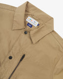 Close up view of Uskees khaki ripstop utility jacket with focus on the collar, popper button and branding label.