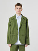 Three-quarter pose of man wearing the Uskees 3047 Docklands coriander green blazer, paired with blue shirt.