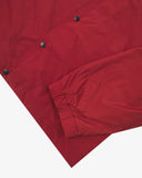 Close up shot of Uskees clay red coach jacket for men showing the elasticated cuff and black poppers.