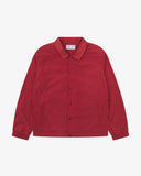 Front flat shot of Uskees clay red coach jacket for men showing sharp, contemporary detailing including slanted welt pockets, cinch hem and popper fastening.