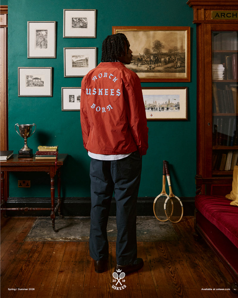 Back view of a man wearing a clay red Uskees jacket with focus on the the North Born Uskees slogan.