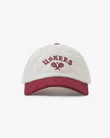 Front view of cream and maroon Uskees 6-panel cap with 'USKEES' and tennis racquet motif embroidered in maroon.