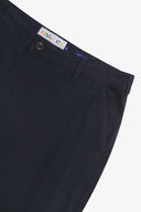 Close up of waist area of twill workwear pants in deep blue. Clear view of front pocket, Corozo button fastening, Uskees branding label and organic cotton twill weave.