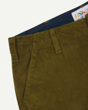 Close-up front view of left front pocket, belt loops, triple stitching, branding label and contrasting lining. Also a closer view of the organic, 11 wale corduroy in woodland green.