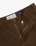 Close up view of Uskees brown corduroy pants showing the brand label, open zip and Corozo button fastening on a white background 