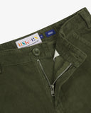Close up view of Uskees green corduroy pants showing the brand label and the zip & button fly fastening detail.