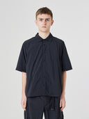 Top-half view of a male model wearing an Uskees black short-sleeve button front trek shirt.