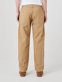 Close-up back view modelling 5021 Uskees men's organic twill khaki painter pants highlighting back patch pockets and gradual, narrowing leg.