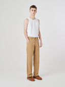 Full-length view modelling 5021 Uskees men's organic twill khaki painter pants paired with white Uskees vest.