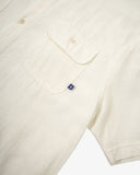 Front close up shot of Uskees cream linen blend short-sleeve shirt showing the chest pocket with brand tab.