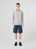Male model wearing an Uskees blue pebble plaid lumberjack shirt and navy shorts.