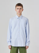 Upper body view wearing Uskees light blue and white striped men's Oxford shirt.