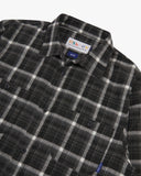 Close up view of an Uskees charcoal check long sleeved flannel shirt for men showing the chest pockets and collar detail.