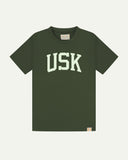 Full flat view of coriander-green organic cotton signature T-shirt for men, showing the varsity inspired 'USK' logo on the chest and the Uskees branding labels on the neck and hem.