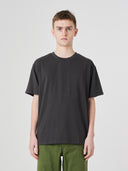 Top-half view of model wearing 7006 faded black organic cotton t-shirt, paired with Uskees green pants