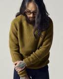 Male model wearing an Uskees woodland green ribbed sweater and midnight blue trousers.
