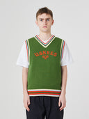 Front view of a male model wearing a bright green sleeveless sweater vest with 'USKEES' branding on the front in red.