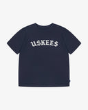 Full flat view of the Uskees navy blue organic cotton T-shirt for men, showing the brand graphics on front and loose silhouette.