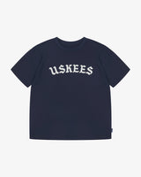 Full flat view of the Uskees navy blue organic cotton T-shirt for men, showing the brand graphics on front and loose silhouette.