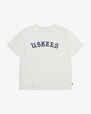 Full flat view of the Uskees white organic cotton T-shirt for men, showing the brand graphics on front and loose silhouette.